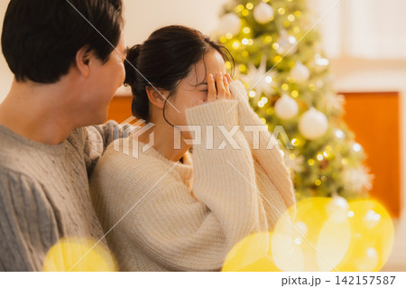 クリスマスのリビングでくつろぐカップル クリスマスのリビングでくつろぐカップル 142157587