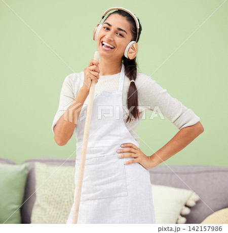 Woman, headphones for cleaning with broom and singing in the home, energy and fun with music for housekeeping. Karaoke, kpop and concert while sweeping, playful or crazy with house work or maid 142157986