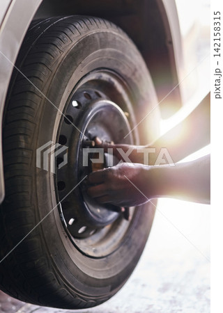 Tyre, hands and mechanic in garage for repairs, rubber and fixing or replace fitting on car at shop. Closeup, person and service or safety check inspection, motor and alignment of vehicle to change Tyre, hands and mechanic in garage for repairs, rubber and fixing or replace fitting on car at shop. Closeup, person and service or safety check inspection, motor and alignment of vehicle to change 142158315