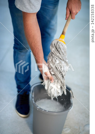 Person, hand and mopping bucket for cleaning with soap as janitor service for health, bacteria or maintenance. Washing, tools and germs equipment for dirty floor or fluid chemical, house or sanitize Person, hand and mopping bucket for cleaning with soap as janitor service for health, bacteria or maintenance. Washing, tools and germs equipment for dirty floor or fluid chemical, house or sanitize 142158338