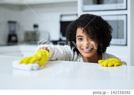 Cleaner, portrait and happy woman in kitchen of home for hygiene, countertop or housekeeping. Cloth, table and face of female maid in apartment for cleaning domestic work, task or wipe surface 142158392