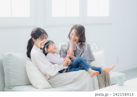 ソファーに座る親子と祖母 ソファーに座る親子と祖母 142158413