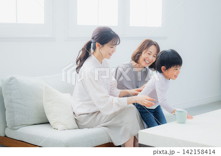 ソファーに座る親子と祖母 ソファーに座る親子と祖母 142158414