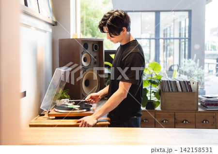 レコードプレイヤーを操作して音楽を楽しむ男性 レコードプレイヤーを操作して音楽を楽しむ男性 142158531