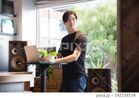 スタンディングデスクを活用し集中してPC作業を行うITエンジニアの男性 142158534