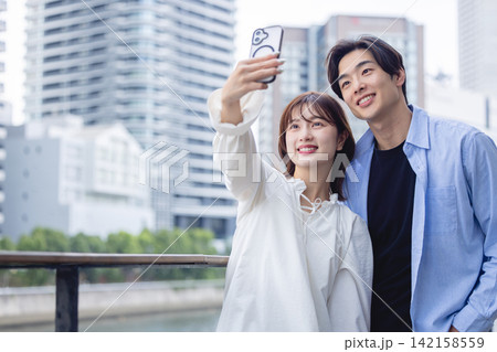 スマートフォンで自撮りをする20代カップル スマートフォンで自撮りをする20代カップル 142158559