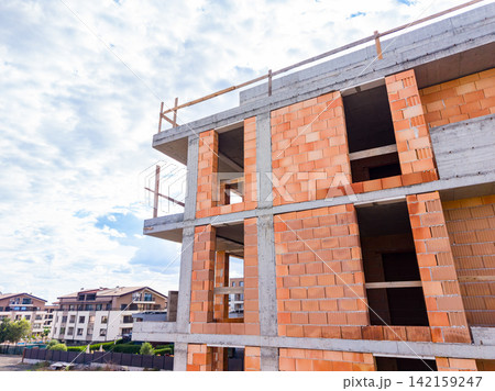 Construction of a new building with unfinished brick walls in a city area during the day 142159247