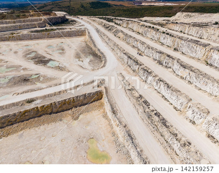 Quarry site showing deep excavations and paths in an open area with stone extraction activity ongoing Quarry site showing deep excavations and paths in an open area with stone extraction activity ongoing 142159257