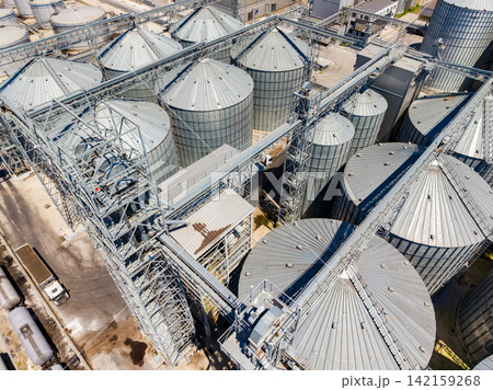 A view of a grain storage facility with silos and machinery in operation during the day 142159268