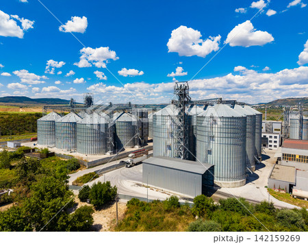 View of grain storage silos under bright blue sky with clouds during daytime View of grain storage silos under bright blue sky with clouds during daytime 142159269