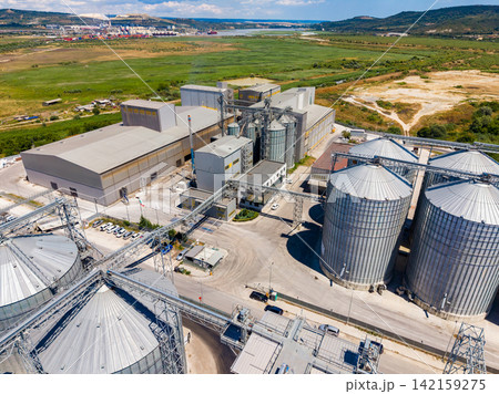 Large industrial facility with silos and machinery in an agricultural area on a clear day 142159275