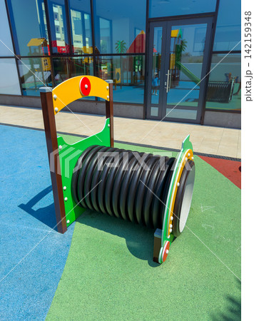 Playground equipment with a colorful design and a large tube located in a children's play area on a sunny day 142159348