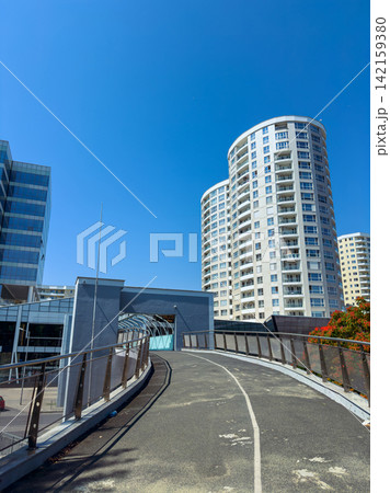 Modern buildings rise against the clear blue sky at a bustling urban location during midday 142159380