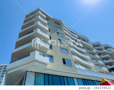 Modern building with multiple balconies and a clear blue sky during daytime in an urban area 142159521