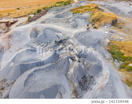 Granite quarry shows machinery and piles of stone at work site during day 142159546