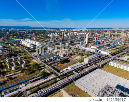 View of an industrial complex with storage tanks and smokestacks in the background during a clear day 142159617