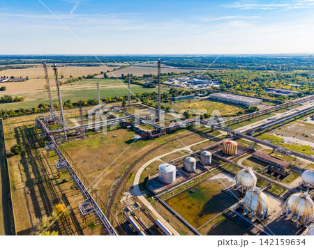 Industrial site with storage tanks and pipelines under a clear blue sky 142159634