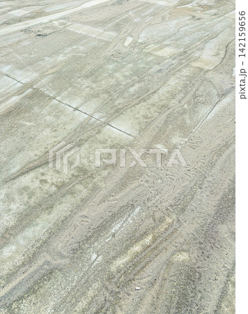 Ground covered with sand showing patterns from movement, taken during daylight in an outdoor location Ground covered with sand showing patterns from movement, taken during daylight in an outdoor location 142159656