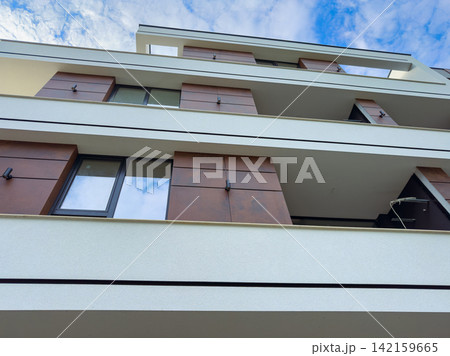 Modern building with balconies under a partly cloudy sky in an urban setting 142159665
