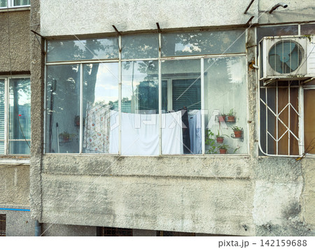 Curtains and clothes hang on a balcony of a residential building on a warm afternoon 142159688