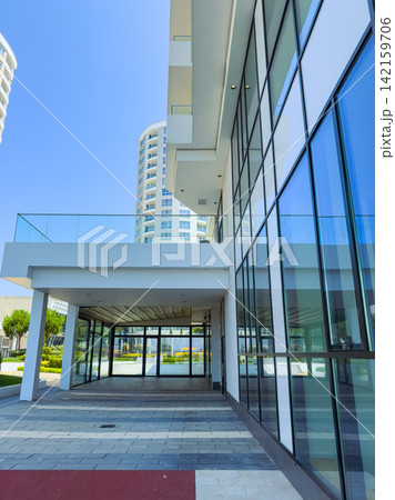Modern building with large glass windows in a city setting under clear blue sky Modern building with large glass windows in a city setting under clear blue sky 142159706