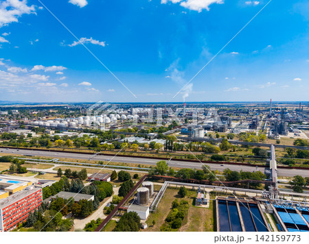 Industrial site in the daytime showing storage tanks, factories, and highways with blue sky and clouds Industrial site in the daytime showing storage tanks, factories, and highways with blue sky and clouds 142159773