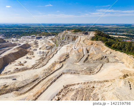 View of a limestone quarry in daylight showing heavy machinery and raw materials at work in the site View of a limestone quarry in daylight showing heavy machinery and raw materials at work in the site 142159798