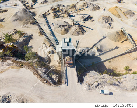 Large construction site shows piles of sand and gravel with machinery working in a wide area during daytime Large construction site shows piles of sand and gravel with machinery working in a wide area during daytime 142159809