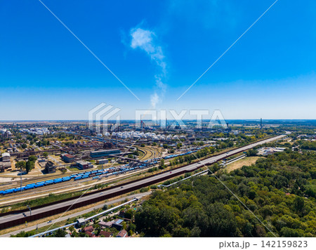 View of industrial area with factories and trains near a river on a clear day View of industrial area with factories and trains near a river on a clear day 142159823