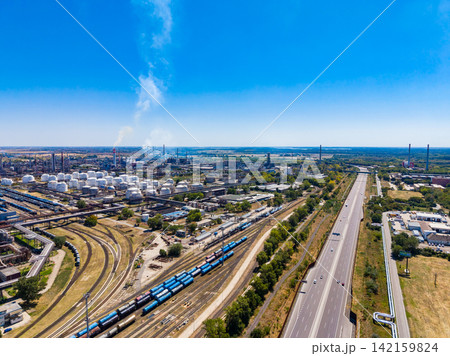 View of industrial area with storage tanks and railway tracks next to highway under clear blue sky View of industrial area with storage tanks and railway tracks next to highway under clear blue sky 142159824