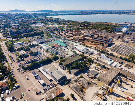 View of a city industrial area with buildings and construction sites near the waterfront during daytime View of a city industrial area with buildings and construction sites near the waterfront during daytime 142159943