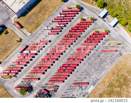 Large parking lot with numerous red buses arranged in rows during daylight hours at a transportation depot Large parking lot with numerous red buses arranged in rows during daylight hours at a transportation depot 142160015