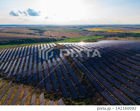 Field of solar panels in sunny landscape with hills and fields in the background during daytime Field of solar panels in sunny landscape with hills and fields in the background during daytime 142160092