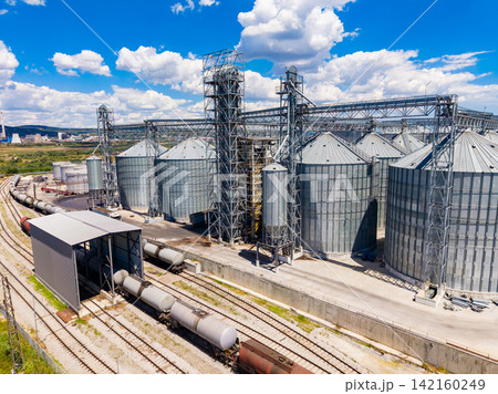 Storage facility with silos and train tracks in a rural area during clear blue sky Storage facility with silos and train tracks in a rural area during clear blue sky 142160249