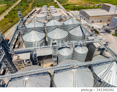Grain storage facility with silos and machinery in agricultural area 142160262