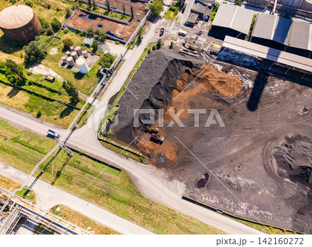 View of an industrial site with storage areas, vehicles, and machinery during daytime in an outdoor setting View of an industrial site with storage areas, vehicles, and machinery during daytime in an outdoor setting 142160272