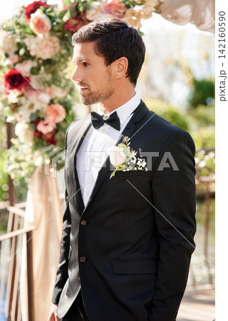 Man, groom and wedding day at reception for marriage commitment with flower arch, ceremony or event. Male person, husband and boutonniere on suit at love celebration for milestone, backyard or bowtie 142160590
