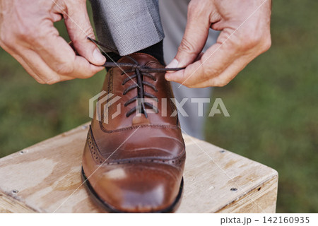 Man, groom and tie laces at outdoor wedding, fashion and formal or elegant style for marriage celebration. Male person, getting ready and preparation for event, party and hands in nature for clothes 142160935