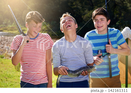 Laugh, boys and friends with fishing and reel, smile and proud on camping holiday. Face, happy and rod and net with gear for fun hobby, young men and dinner caught on vacation by river with mates Laugh, boys and friends with fishing and reel, smile and proud on camping holiday. Face, happy and rod and net with gear for fun hobby, young men and dinner caught on vacation by river with mates 142161311
