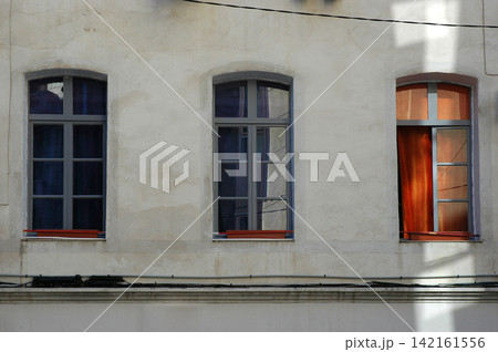 Three vintage windows on a concrete building facade 142161556