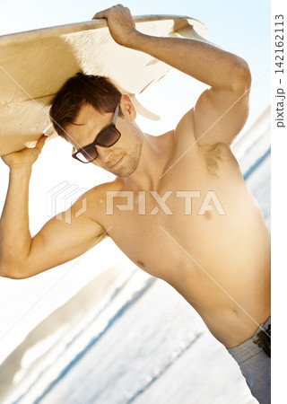 Man, surfing and sunglasses at ocean with sunny for summer vacation, sport activity and travel. Surfer, topless and eyewear with surfboard at beach for sunshine, island holiday and muscular in Brazil 142162113