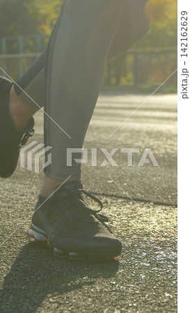 Vertical video. Close up. Pretty sporty woman running in the sports stadium. Happy sportswoman enjoys her workout and stays active outdoors. Vertical video. Close up. Pretty sporty woman running in the sports stadium. Happy sportswoman enjoys her workout and stays active outdoors. 142162629