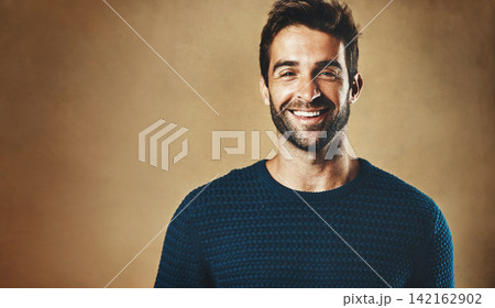 Smile, portrait and man with clothes for fashion, style and casual wear isolated on brown background. Face, happy or model with trendy sweater, closeup and cool person in studio backdrop with mockup 142162902