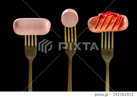 Raw and grilled sausage on forks isolated on black background Raw and grilled sausage on forks isolated on black background 142162911
