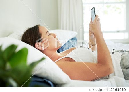 Woman, home and lying in bed with smartphone on break for social media, texting and networking. Female person, bedroom and cellphone on holiday or day off to relax, chill and calm with online dating Woman, home and lying in bed with smartphone on break for social media, texting and networking. Female person, bedroom and cellphone on holiday or day off to relax, chill and calm with online dating 142163010