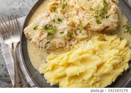 Zwiebel schnitzel pork with onion cream sauce with mashed potatoes garnish close-up in a plate. Horizontal top view Zwiebel schnitzel pork with onion cream sauce with mashed potatoes garnish close-up in a plate. Horizontal top view 142163179