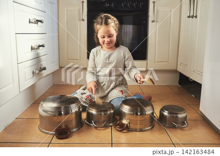 Home, instrument and child drums with music in kitchen and creativity on holiday or vacation. Kid, drummer and development of musician with noise, sound and girl playing concert on floor in house 142163484
