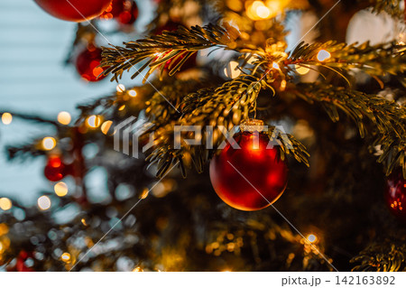 Purple glitter Christmas ornament on tree branch with warm bokeh lights Purple glitter Christmas ornament on tree branch with warm bokeh lights 142163892