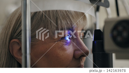 Patient, slit lamp or ophthalmology as eye test, medicine or optometry as healthcare technology. Mature woman, eyeball or light in glaucoma, exam or consultation to diagnose lens, cornea or myopia Patient, slit lamp or ophthalmology as eye test, medicine or optometry as healthcare technology. Mature woman, eyeball or light in glaucoma, exam or consultation to diagnose lens, cornea or myopia 142163978