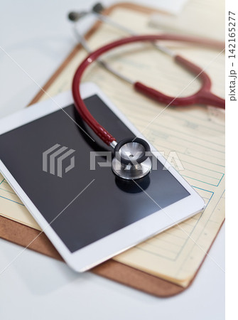 Hospital, clinic and tablet with stethoscope on desk for medical website, telehealth and research. Healthcare, cardiology and digital tech, equipment and clipboard for online consulting service 142165277
